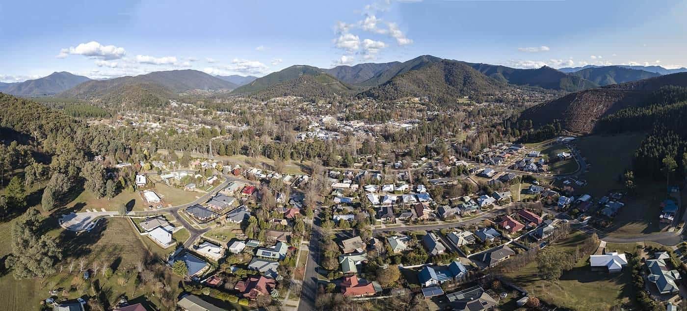 Aerial panorama of Bright, Victoria, in a green valley at the foot of forested mountains
