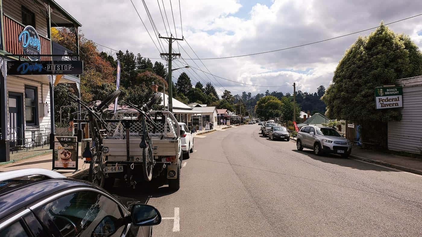 The main street of Derby in Tasmania with old buildings and forested hills behind