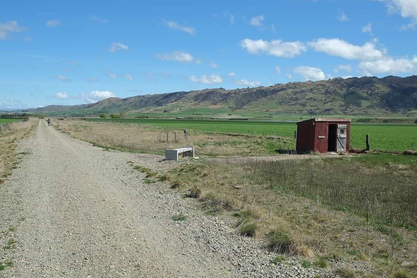 The Otago Central Rail Trail crossing the wide, dry Ida Valley with mountains in the distance