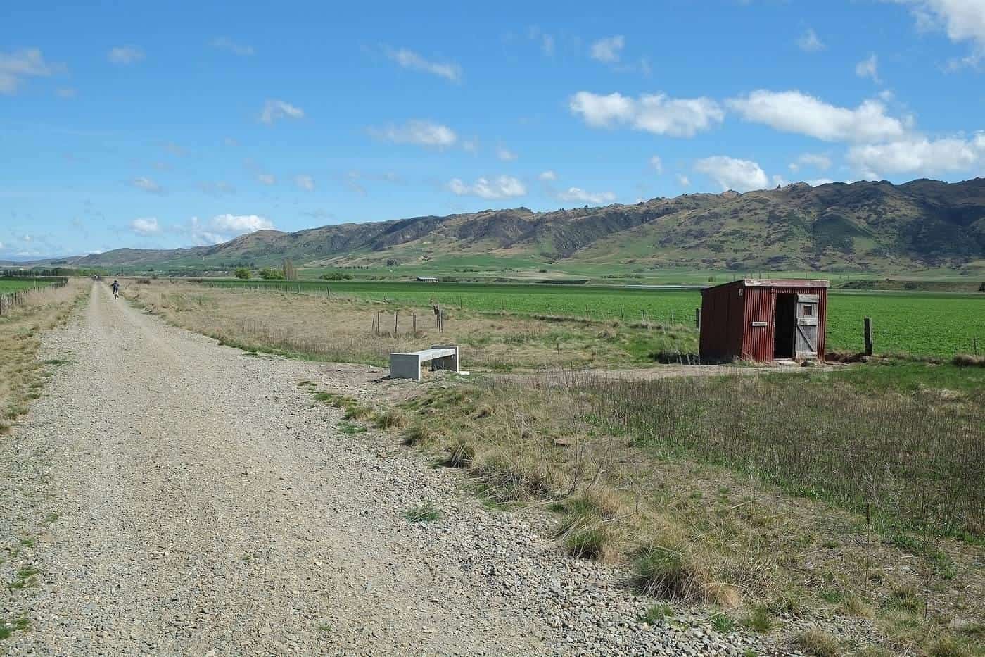 The Otago Central Rail Trail crossing the wide, dry Ida Valley with mountains in the distance