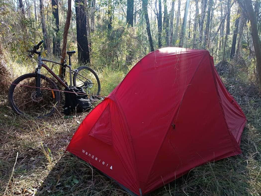 A loaded touring bicycle parked beside a tent in Australian bush